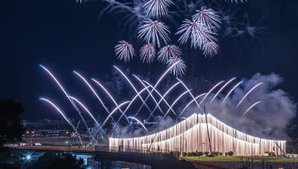 大規模な花火大会の夜景、橋の上に流れる花火と美しい打ち上げ花火のコラボレーション