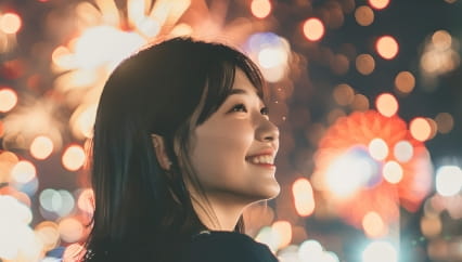 花火大会で楽しむ女性の笑顔、色鮮やかな花火が夜空を照らす