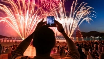 花火大会でスマホを構える観客、燃え上がる花火を撮影する様子